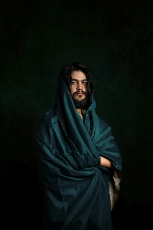 a man wrapped in a blanket in a dark room, an album cover, inspired by Caravaggio, renaissance, an afghan male type, jesus, ((portrait)), promotional image