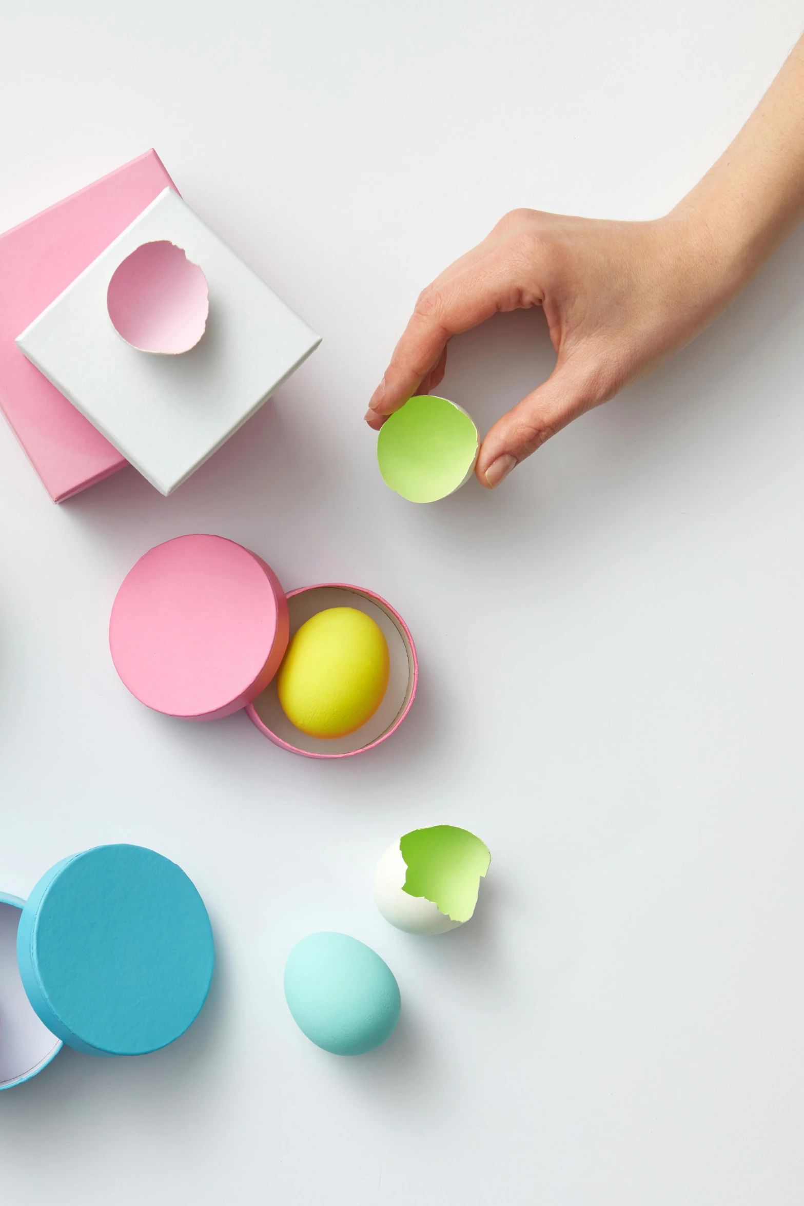 a person reaching for an egg in a box, by Eden Box, paper cutouts of plain colors, sleek round shapes, product introduction photo, candy pastel