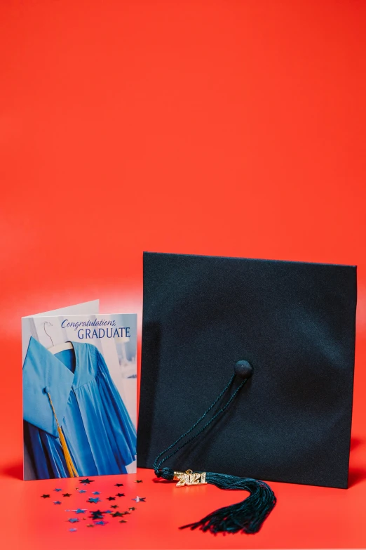 a graduation cap and diploma on a red background, by Carey Morris, pexels contest winner, dressed in red paper bags, blue robes, color photograph, matte black paper