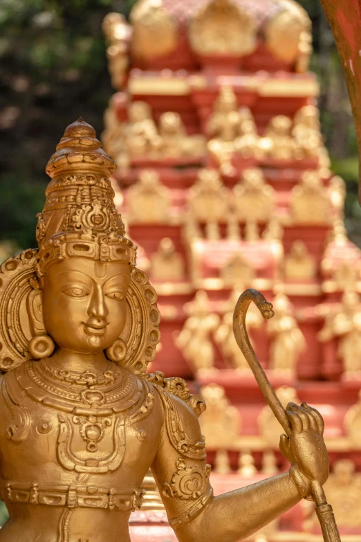 a statue of a woman holding a staff, a statue, standing in a hindu kovil, gold waterfalls, intricate 8 k detail, sun god