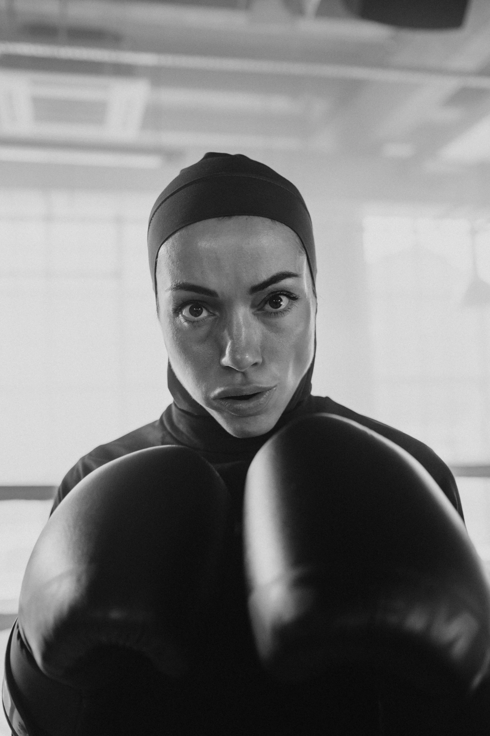 a black and white photo of a woman with boxing gloves, a black and white photo, by irakli nadar, pexels contest winner, young middle eastern woman, charli xcx, balaclava, advertising photo