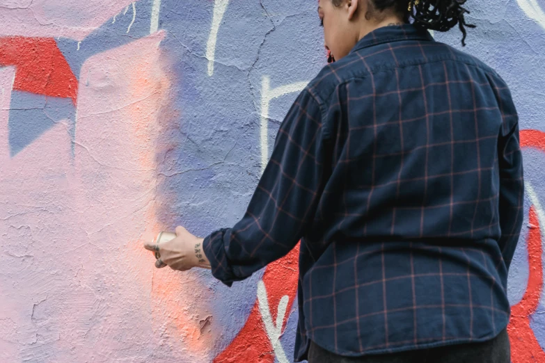 a man standing in front of a graffiti covered wall, a painting, inspired by Gerard Sekoto, pexels contest winner, holding a paintbrush in his hand, painting of a woman, filling the frame, red paint