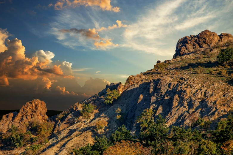 a mountain covered in rocks and trees under a cloudy sky, by Koloman Sokol, pexels contest winner, romanticism, golden hour photo, greek fantasy landscape, thumbnail, vray beautiful