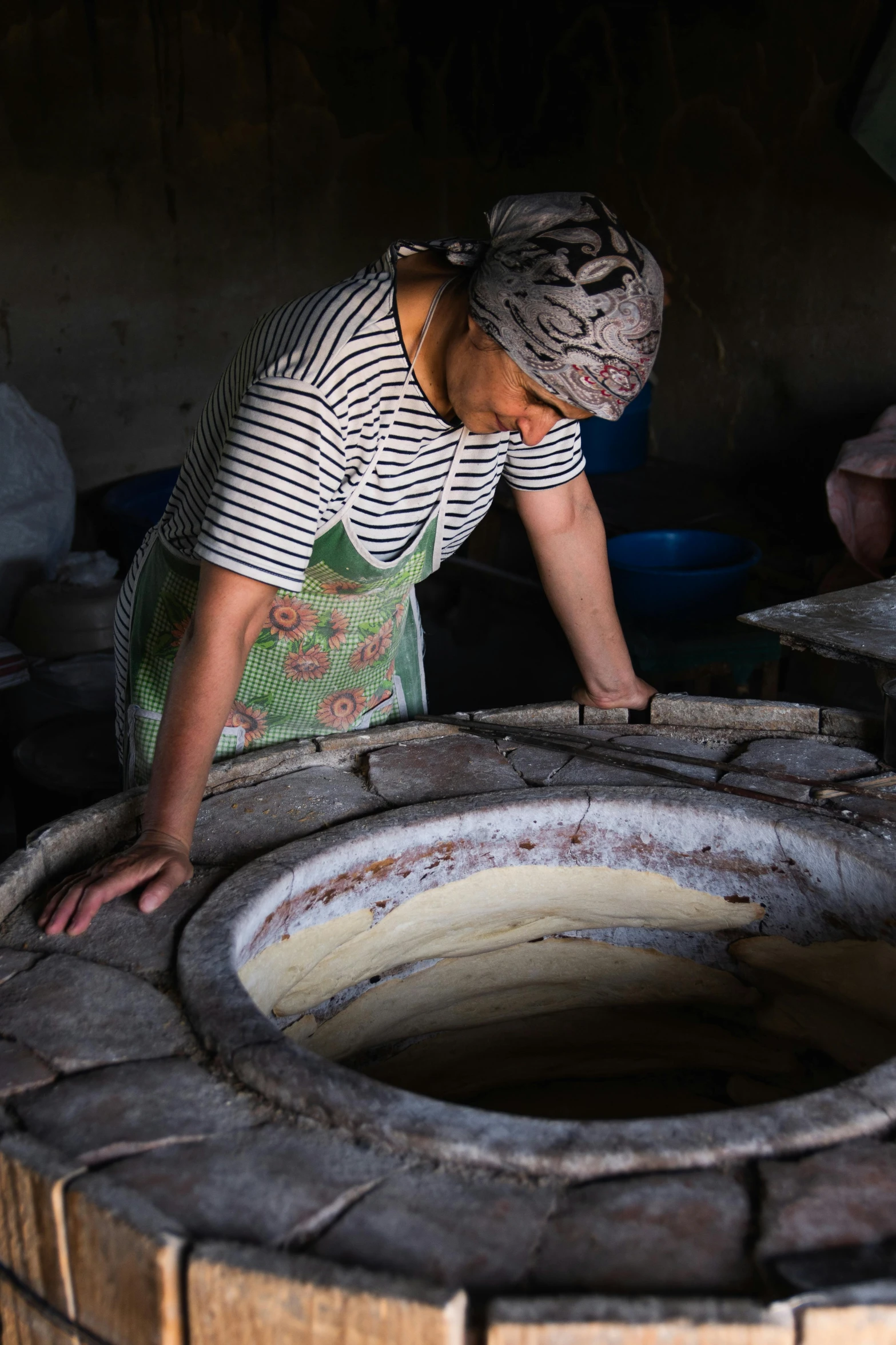 a woman standing in front of a brick oven, process art, indonesia, circle pit, grey, ceramic