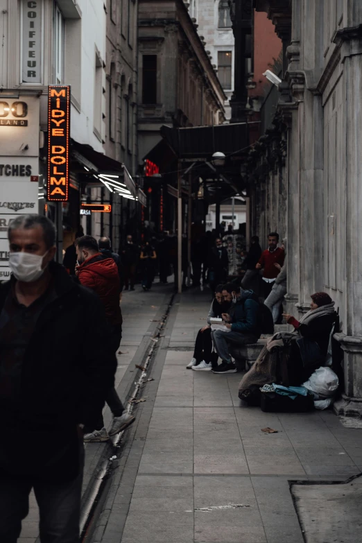 a group of people walking down a street next to tall buildings, a photo, pexels contest winner, hyperrealism, istanbul, old man doing with mask, dark alleyway, low quality video