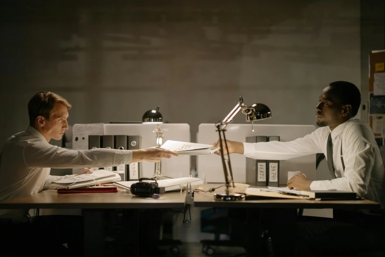 a couple of men sitting at a table, pexels contest winner, photorealism, office background, reaching out to each other, production still, under a spotlight