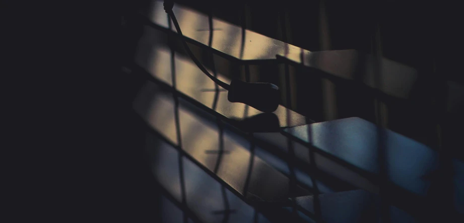 a close up of a window with blinds, an album cover, inspired by Elsa Bleda, unsplash, dark cables hanging from ceiling, beautiful shadows, spying, microphone silluette