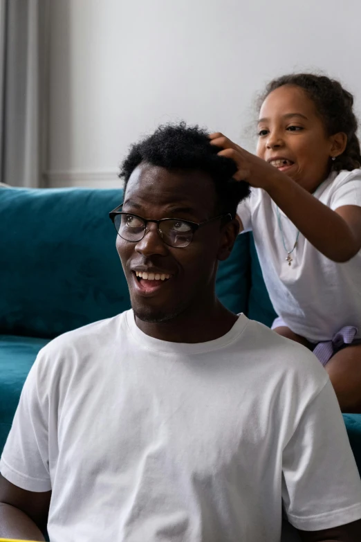 a man and a little girl sitting on a couch, by Samuel Washington Weis, pexels contest winner, hurufiyya, diverse haircuts, frosting on head and shoulders, adut akech, slide show