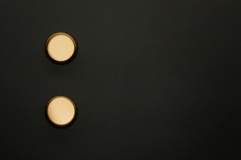 a couple of buttons sitting on top of a black surface, an album cover, inspired by Lucio Fontana, deviantart, minimalism, black gold, shot on sony a 7, rivets, 3 4 5 3 1