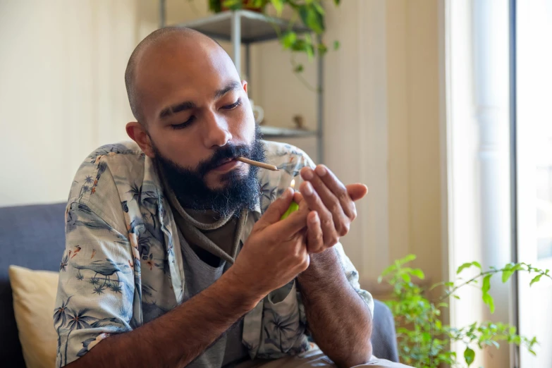 a man sitting on a couch with a cigarette in his mouth, inspired by Hovsep Pushman, pexels contest winner, marijuana greenery, aboriginal australian hipster, bald man, profile image