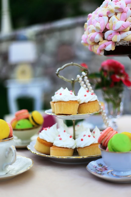 a table topped with lots of different types of cupcakes, inspired by Rudolf von Alt, unsplash, renaissance, tea cup, al fresco, alice in wonderland theme, splash image