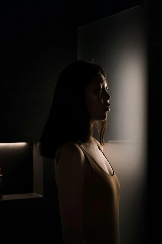 a woman standing in front of a mirror in a dark room, yun ling, backlit face, ( ( theatrical ) ), cinematic image