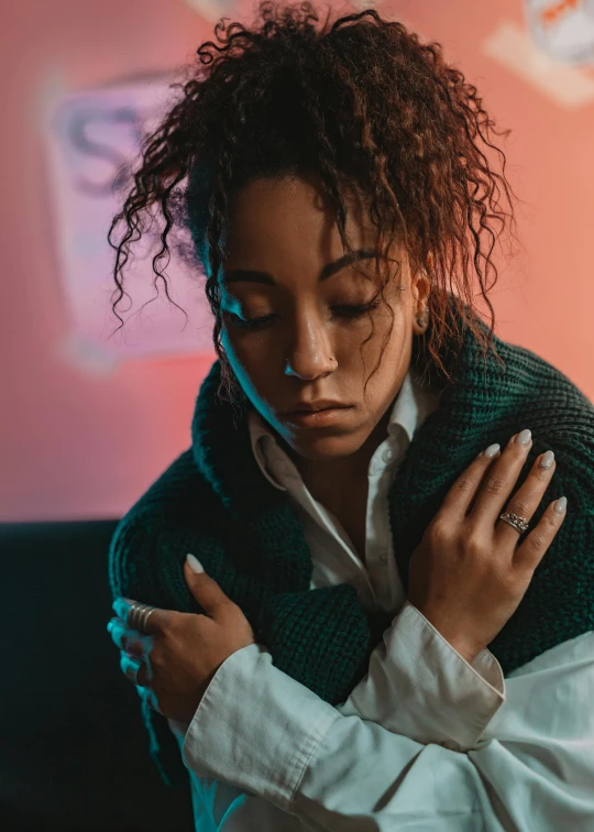 a woman in a white shirt and green scarf, an album cover, trending on pexels, emotional pain, bisexual lighting, mixed-race woman, comforting