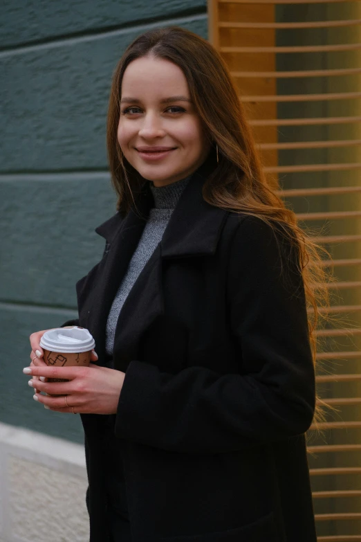 a woman in a black coat holding a cup of coffee, pokimane, professional profile photo