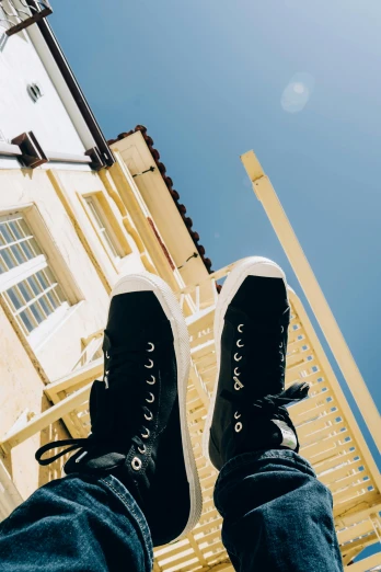 a person wearing black sneakers standing in front of a building, unsplash contest winner, photorealism, towering high up over your view, oceanside, bright sunny day, (high contrast)