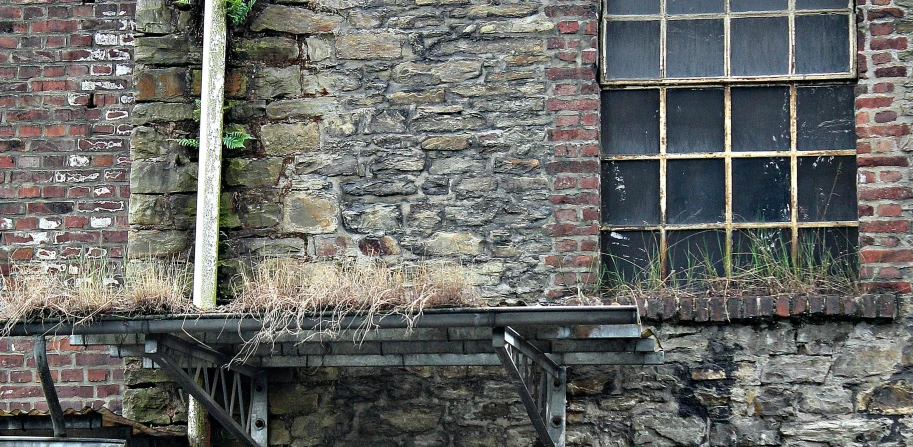 a car parked in front of a brick building, an album cover, inspired by Thomas Struth, pexels contest winner, renaissance, ferns and mold on concrete, built on a steep hill, industrial colours, stone roof