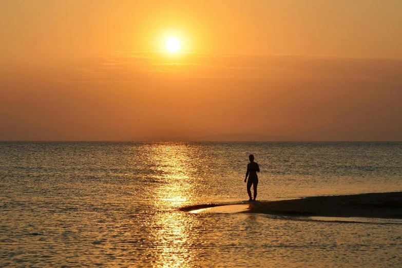 a person walking on a beach at sunset, heat shimmering, ((sunset)), red sea, a single