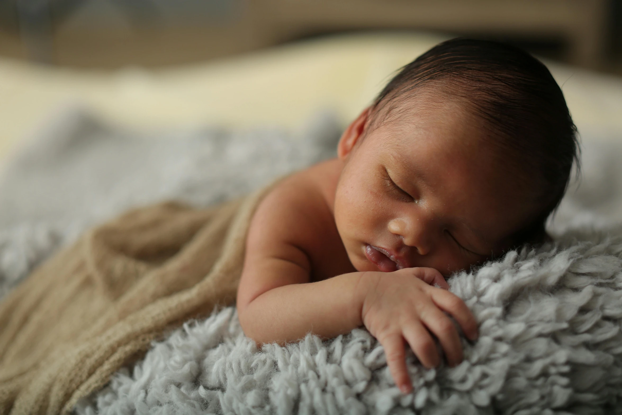 a baby sleeping on a blanket on a bed, by Alice Mason, shutterstock contest winner, mixed race, grey, brown, over-shoulder shot