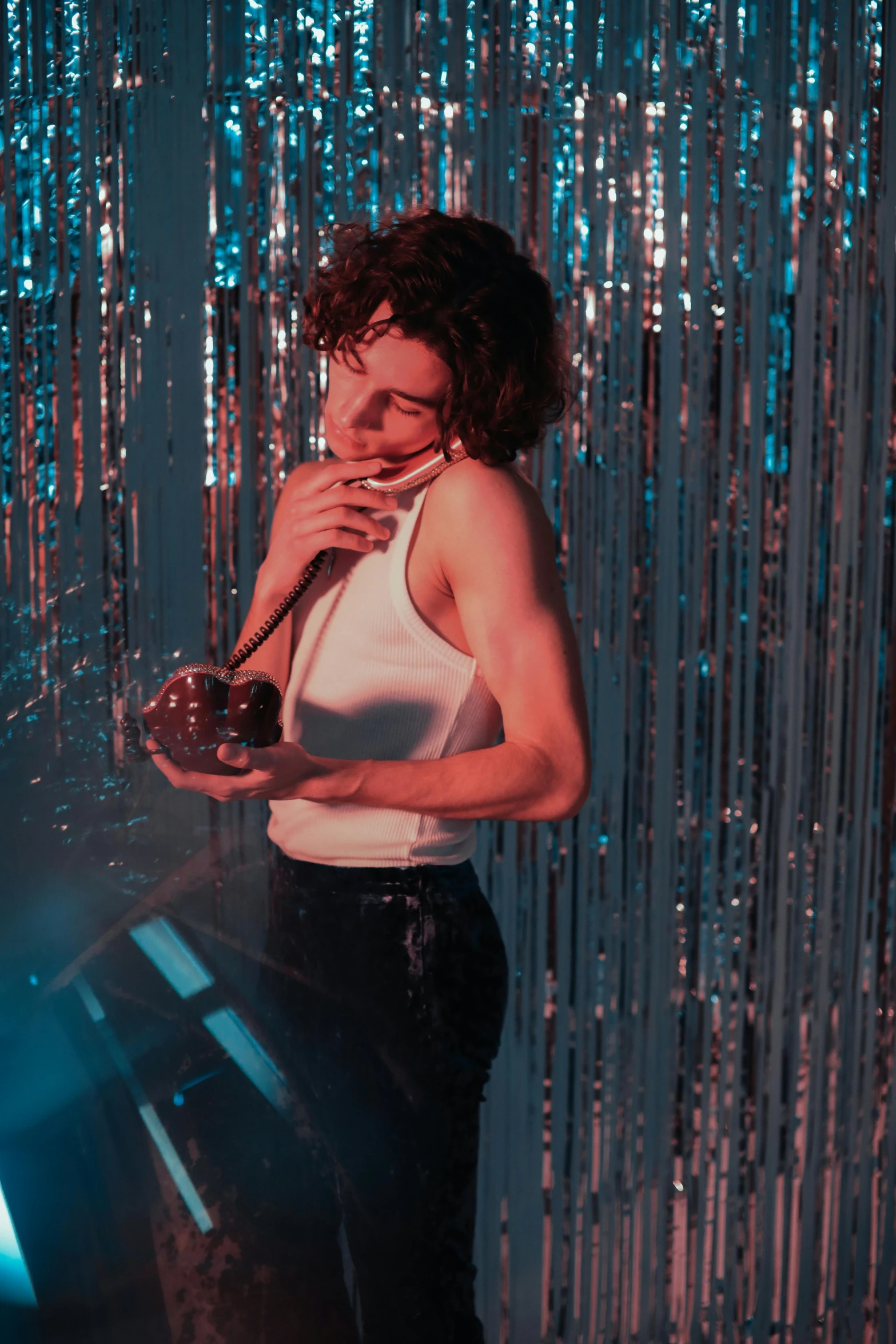 a woman standing in front of a mirror talking on a cell phone, an album cover, inspired by Nan Goldin, trending on pexels, magical realism, disco ball, curly and short top hair, smoking woman, joe keery