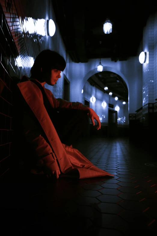 a person sitting on the ground in a dark hallway, an album cover, inspired by Osman Hamdi Bey, unsplash, china town blade runner, declan mckenna, colored photo, sergey krasovskiy