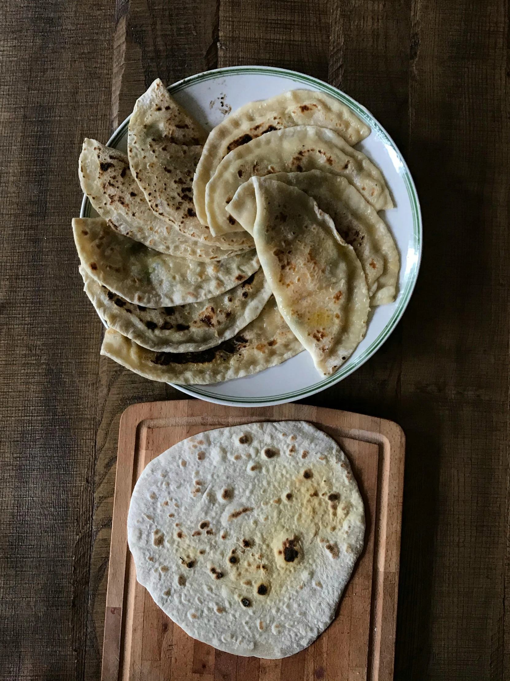 a wooden cutting board topped with tortillas next to a plate of tortillas, by Alice Mason, reddit, sri lanka, portrait image