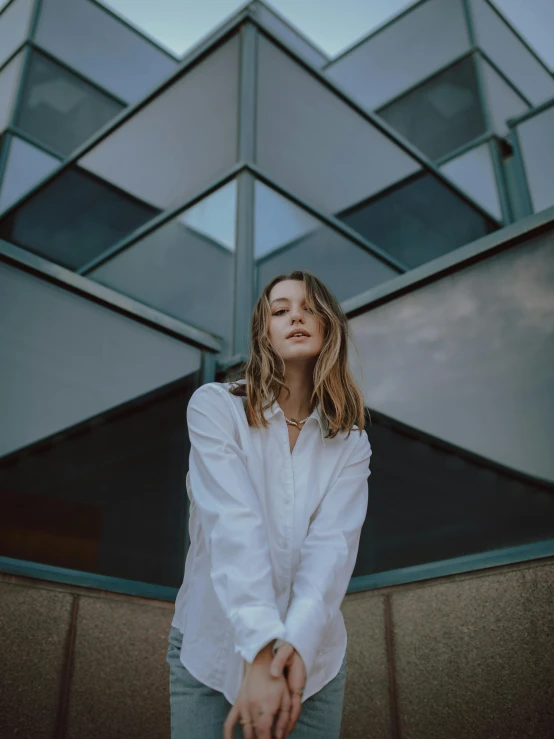 a woman standing in front of a building, trending on unsplash, wearing a white button up shirt, aurora aksnes, high quality photo, pokimane