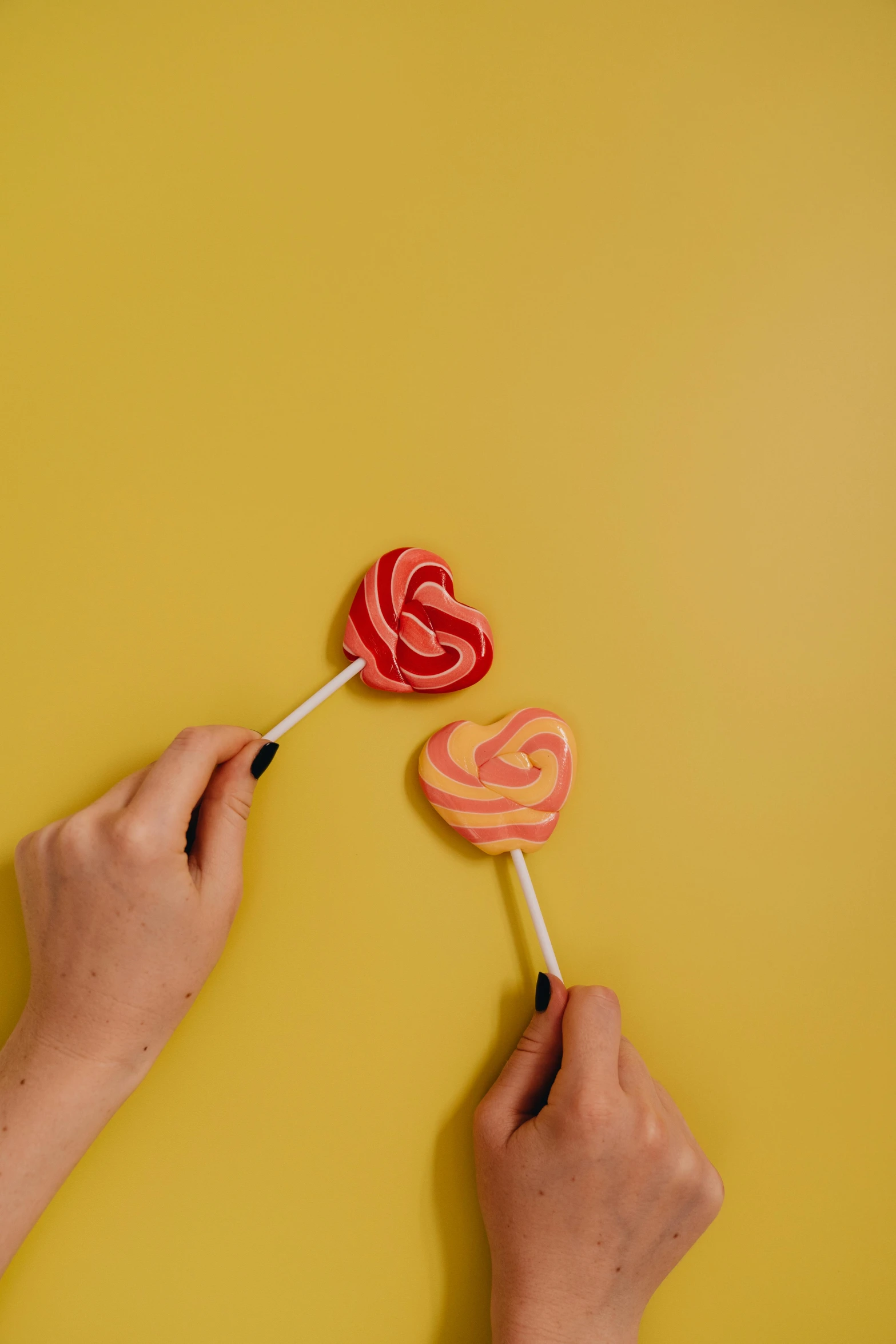 two hands holding lollipops against a yellow background, a picture, pexels, carved soap, instagram picture, swirly, profile image