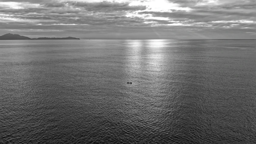 a lone boat in the middle of a large body of water, a photo, inspired by Max Dupain, unsplash contest winner, wellington, overlooking the ocean, silver light, bird view