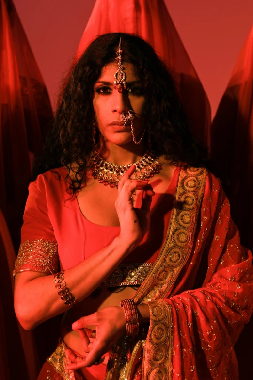 a woman in a red sari posing for a picture, an album cover, transgressive art, trans rights, [ theatrical ], red lighting, wearing ornate clothing