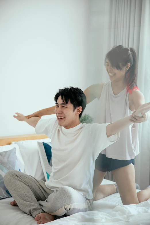 a man sitting on top of a bed next to a woman, inspired by Gong Kai, pexels contest winner, happening, arms out, casual game, smiling and dancing, medium shot of two characters