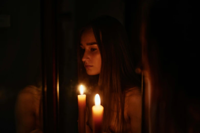 a woman holding a lit candle in front of a mirror, inspired by Elsa Bleda, pexels contest winner, teenage girl, lilly collins, profile image, haunted sad expression