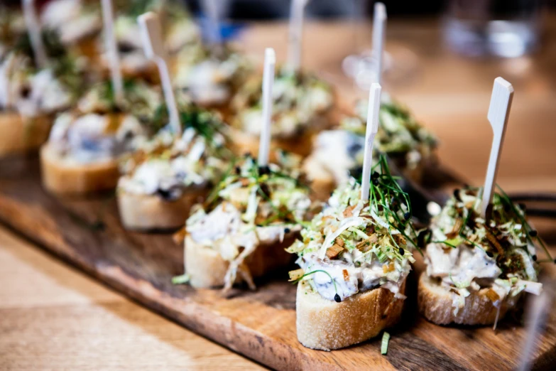 a wooden cutting board topped with small appetizers, inspired by Richmond Barthé, unsplash, renaissance, holding a baguette, melbourne, creamy, jajaboonords flipjimtots