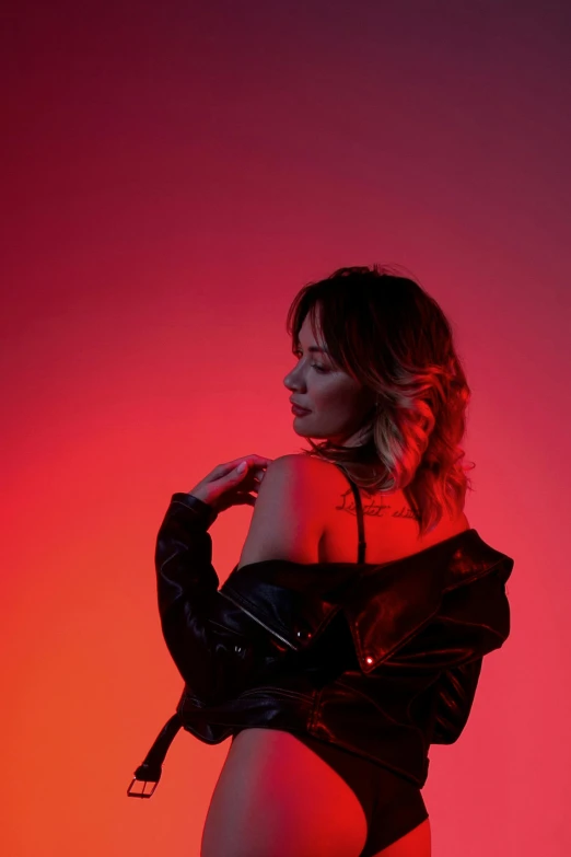 a woman standing in front of a red light, an album cover, inspired by Elsa Bleda, trending on pexels, realism, isabela moner, leather clothes, profile pose, dramatic gradient lighting