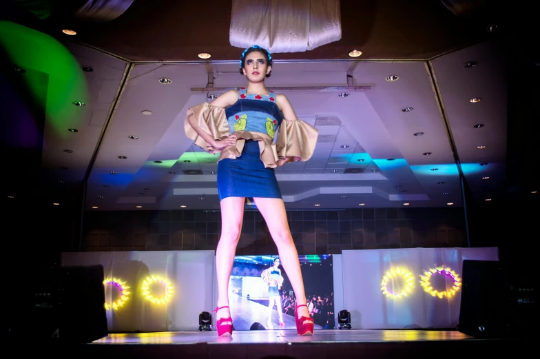 a woman that is standing on a stage, high fashion themed, rafeal albuquerque, blue and yellow lighting, runway photo