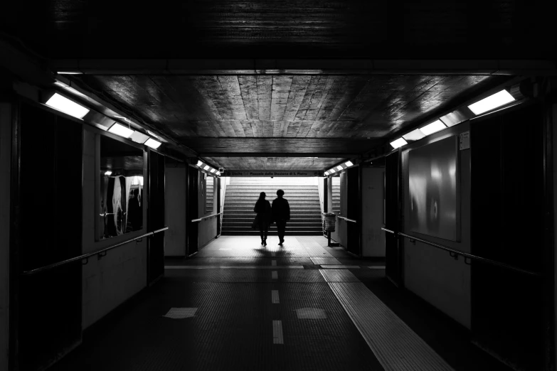 a couple of people that are standing in a tunnel, a black and white photo, by Raphaël Collin, unsplash contest winner, bus station, dark scifi, platform, led