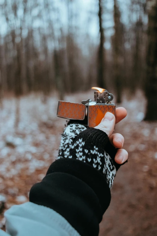 a person holding a lighter in their hand, by Adam Marczyński, pexels contest winner, in the wood, mittens, rectangle, instagram picture