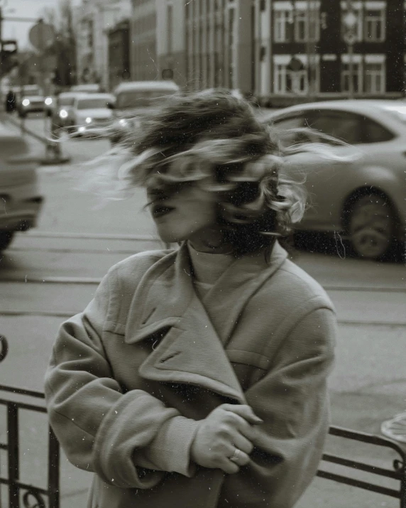 a black and white photo of a woman walking down the street, inspired by Garry Winogrand, trending on unsplash, happening, windy hair, lo fi colors, non binary model, she wears a jacket