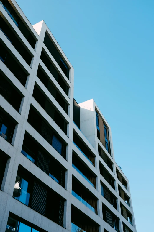 a very tall building with lots of windows, by Washington Allston, unsplash, modernism, concrete housing, 15081959 21121991 01012000 4k, clear blue skies, square