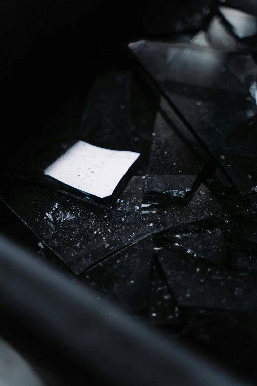 a broken cell phone sitting on top of a table, an album cover, by Jacob Toorenvliet, unsplash, happening, vantablack chiaroscuro, glass debris pieces, square shapes, up-close