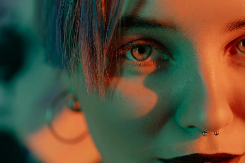 a close up of a woman with piercings, digital art, inspired by Elsa Bleda, trending on pexels, orange teal lighting, shot on anamorphic lenses, high angle closeup portrait, androgynous face