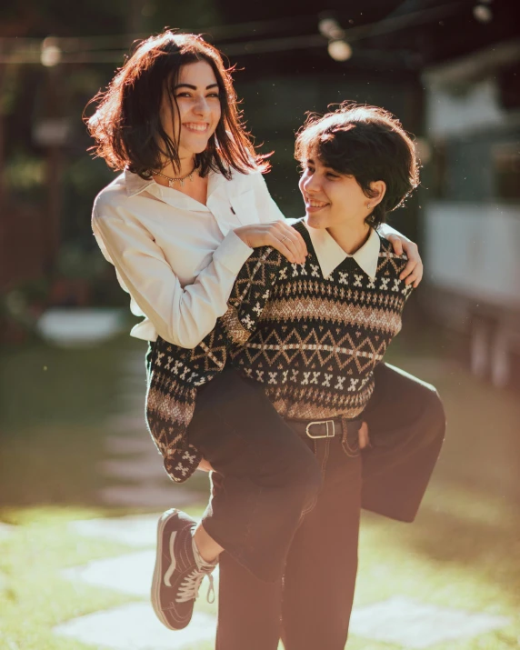 a man carrying a woman on his back, a colorized photo, by Julia Pishtar, pexels contest winner, sweater, lesbians, lawn, brunettes