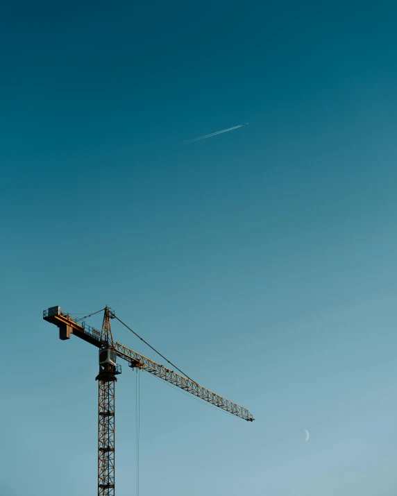 a crane sitting on top of a building under a blue sky, a screenshot, pexels contest winner, constructivism, plain background, ground breaking, photo for magazine, tall thin