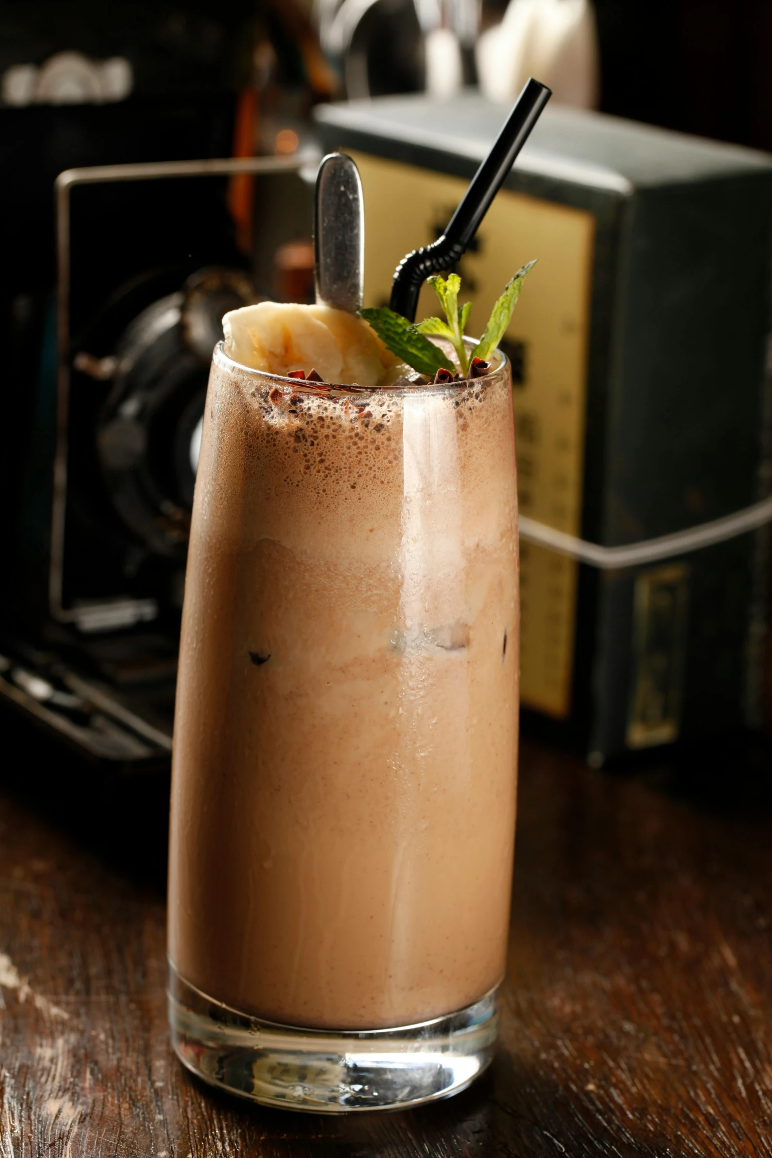 a drink sitting on top of a wooden table, chocolate, banana, mint, hurricane