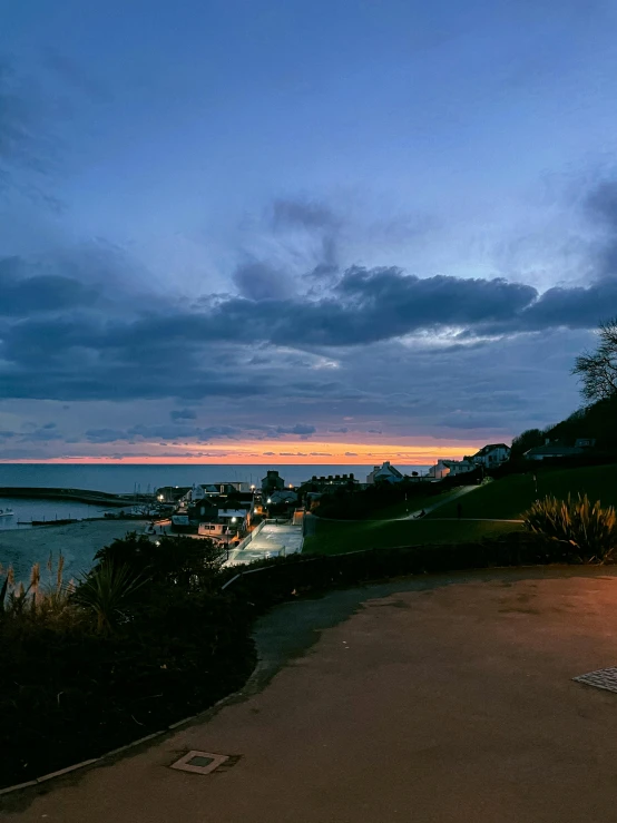 a bench sitting on top of a sandy beach next to the ocean, during a sunset, a road leading to the lighthouse, manly, night time photograph