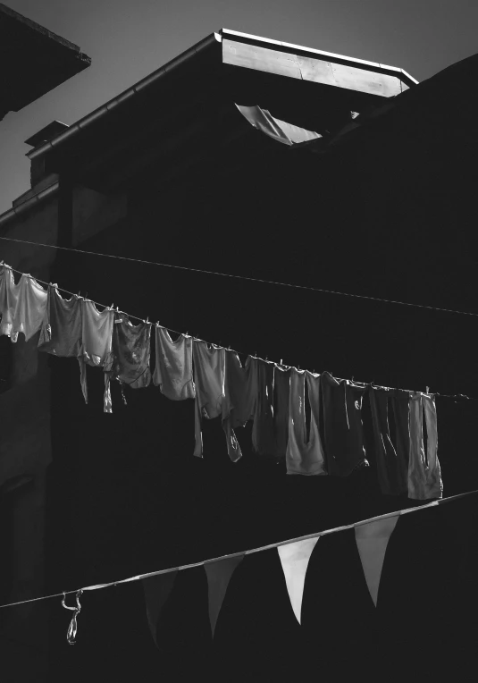 a black and white photo of clothes hanging out to dry, inspired by Arnold Newman, unsplash contest winner, in a dark alley, gang flags, medium format. soft light, 15081959 21121991 01012000 4k