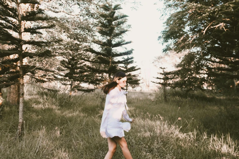 a woman walking through a field of tall grass, unsplash, happening, next to a tree, pale light, background image, cute photo