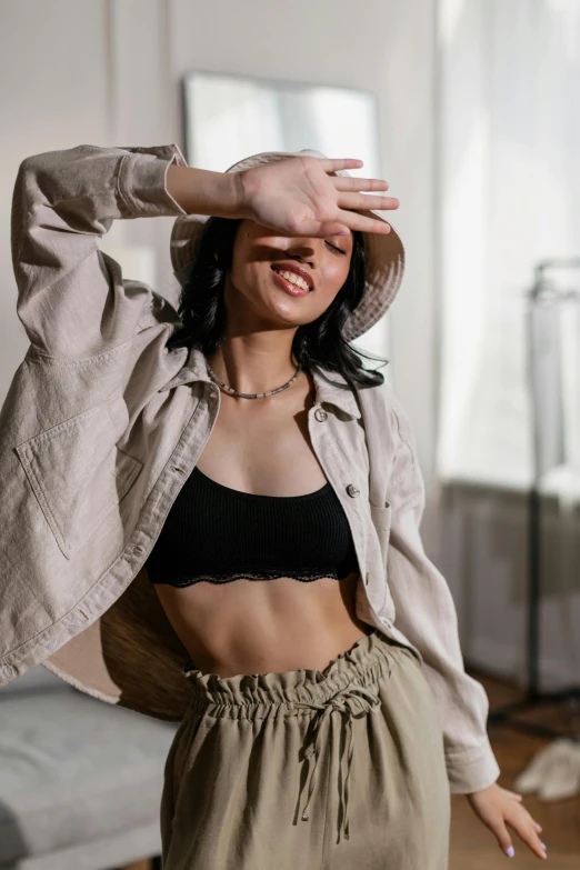 a woman in a black bra top and khaki pants, by Emma Andijewska, trending on pexels, hat and hoodie, happy vibes, young asian woman, bare midriff