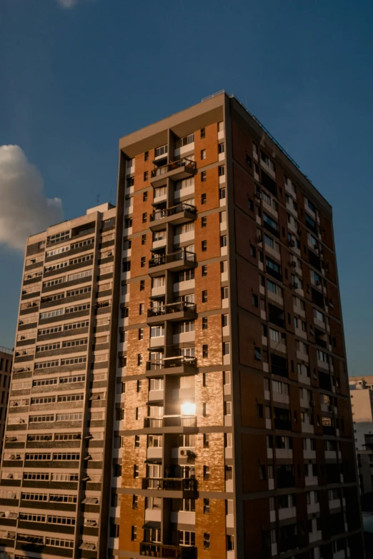 a tall building sitting in the middle of a city, unsplash, brutalism, golden hour 8k, buenos aires, 8k 28mm cinematic photo, brown