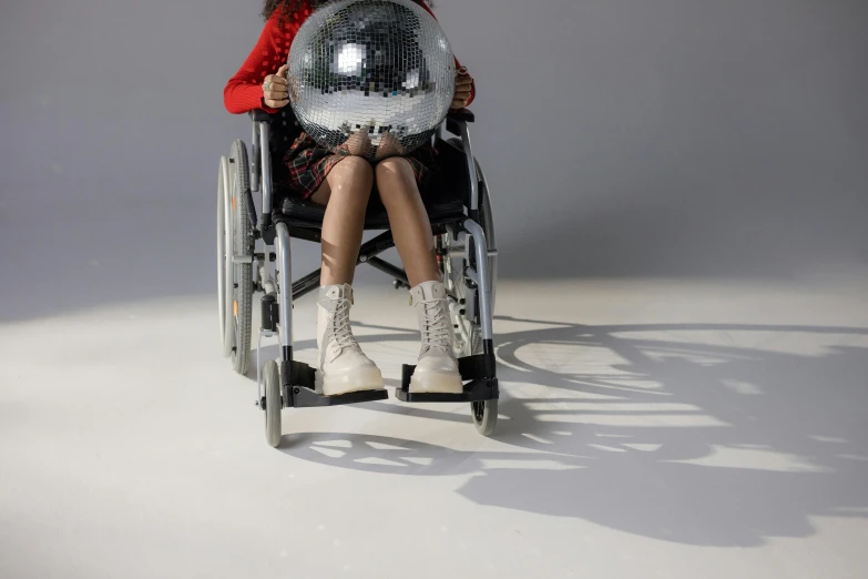 a woman in a wheelchair holding a disco ball, shutterstock contest winner, hyperrealism, sitting on bent knees, press shot, concept photo, 'untitled 9 '