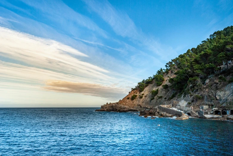 a large body of water next to a cliff, by Julian Allen, unsplash, renaissance, ibiza, 2 5 6 x 2 5 6 pixels, early evening, blue skies